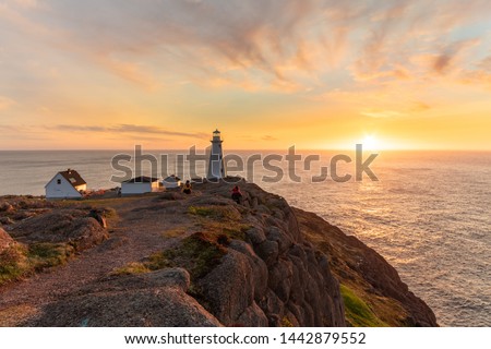 Beautiful sunrise over a white lighthouse sitting at the edge of a rocky cliff. Cape Spear National Historic Site, St Johns Newfoundland. 