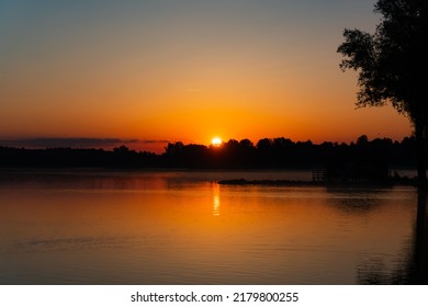 beautiful sunrise in Rimsting at the lake "Chiemsee", in the backgorund is a forest and a little house as silhouettes