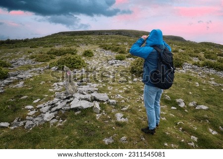 beautiful sunrise scenery with man in blue jacket hiking on top of the mountain at Lough avalla farm loop in Burren National Park, county Clare, Ireland 
