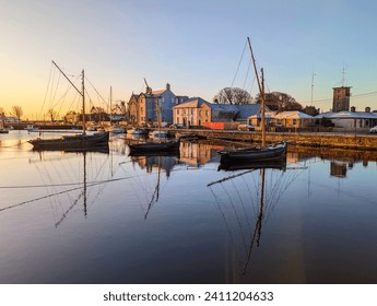 Beautiful sunrise scenery with old wooden boats Galway hookers reflected in water at Claddagh in Galway city, Ireland 