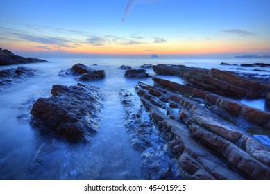 Beautiful sunrise scenery of a rocky beach on northern coast of Taiwan with an island on distant horizon & peculiar rock formations on seashore under dramatic dawning sky (Long Exposure Effect) - Powered by Shutterstock