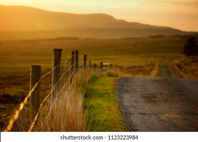 Beautiful sunset in Connemara. Scenic Irish countryside road leading towards magnificent mountains, County Galway, Ireland.