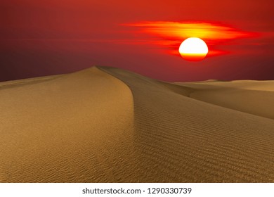 Beautiful sunset in the desert. Sand dune on the background of the setting sun