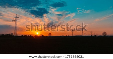 Beautiful sunset with dramatic clouds and powerlines near Tabertshausen, Bavaria, Germany