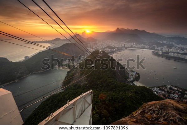 Beautiful sunset landscape with city and mountains\
seen from the Sugar Loaf mountain during sunset time in Rio de\
Janeiro, Brazil