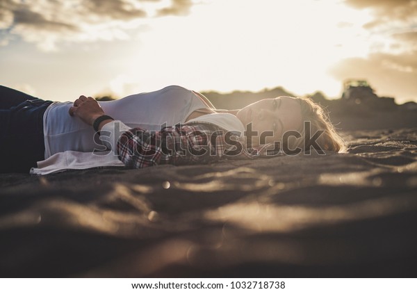 Beautiful sunset light for a cute blonde girl\
lay down rest on the beach in Tenerife. She look at you. Off road\
car parked on the\
background