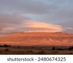 Beautiful sunset looking at Mauna Kea with circular clouds above and the pastures of Pu