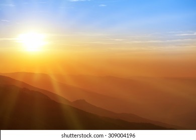 Beautiful sunset in the mountains. Colorful landscape with sun, sunrays and blue sky