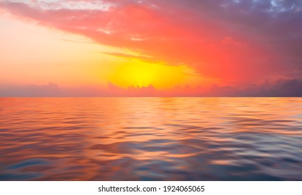 A beautiful sunset over the calm sea with red and orange clouds reflecting in the water