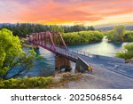 Beautiful sunset over the Clyde bridge on the river Clutha with Southern Alps peaks on the horizon, New Zealand