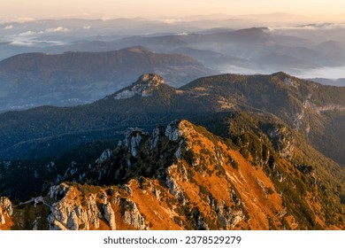 Beautiful sunset over mountain range with rocky terrain and greenery.Sun is setting behind mountains, casting warm glow over landscape.