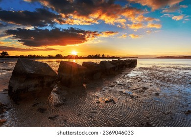 Beautiful sunset over old WWII tank traps in Bramble Bush Bay at Studland on the Isle of Purbeck in Dorset