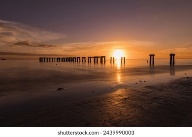 Beautiful sunset over the remains of fishing pier beams in Fort Myers Beach, Gulf Coast, Florida. Colorful sunset. - Powered by Shutterstock