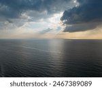 Beautiful sunset over the sea, ocean. Top view from a quadcopter. Beautiful flight. Ships and windmills on the horizon. The rays of the sun break through the clouds.