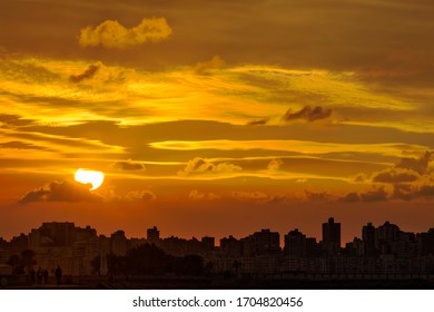 Beautiful sunset over silhouette of arabic town. Silhouette of city with clouds in orange sky during sunset.