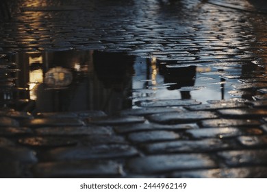 Beautiful Sunset Reflection in Puddle on Old City Cobblestone Street
