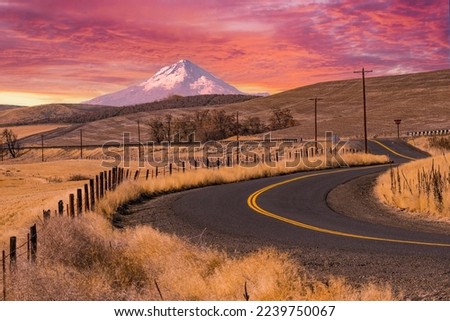 Beautiful sunset sky over Pacific Northwest snow capped Mt. Hood, prairie land and road.