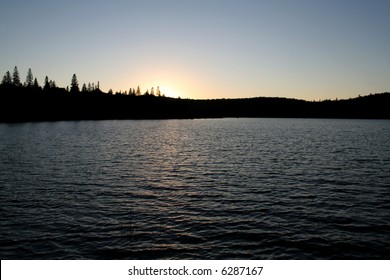 A Beautiful Sunset With The Treeline Silhouette Over A Lake In Algonguin Park In Ontario, Canada.