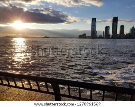 A beautiful sunset from the view of New York City overlooking the harbor. Beautiful cityscape of NewJersey on the opposite side of the river.