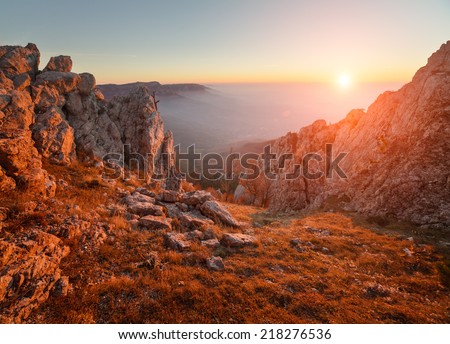 Beautiful sunsets in the autumn alpine mountains. The cloudy sky and fog above the sea. Mystical landscape. It is photographed from a tourist track.