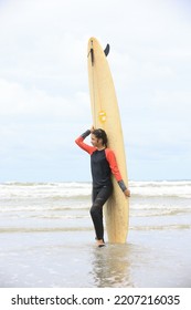 Beautiful Surfer Asian Girl On The Beach . Asian Woman Playing Surf On Sunlight.