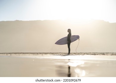 Beautiful surfer girl at the beach standing with her surfboard at sunset time. Female surfer  - Powered by Shutterstock