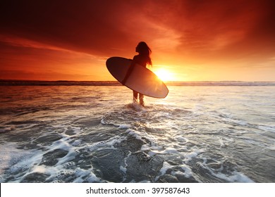 Beautiful surfer woman on the beach at sunset - Powered by Shutterstock