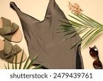 Beautiful swimsuit, palm leaves, sunglasses and slippers on beige background, flat lay
