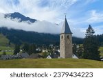 Beautiful swiss alpine countryside with a medieval bell tower and Rothorn mountain on background in Churwalden village in Switzerland. Formerly Parpan