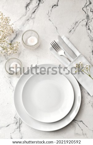 Beautiful table setting with burning candles and floral decor on light background