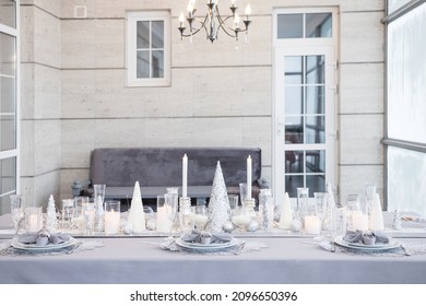 Beautiful table setting with Christmas decorations. Silver colors. Interior of the room
