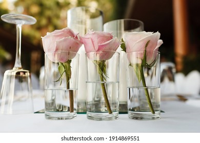 Beautiful table setting with flowers, candles, golden cutlery and white tablecloth.