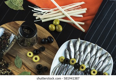 Beautiful table setting on the table from a small fish of the sprat, seasonings and olives