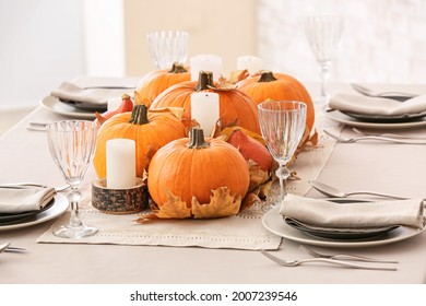 Beautiful Table Setting With Pumpkins And Autumn Leaves In Dining Room