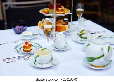 Beautiful Table Setting With Selection Of Sandwiches, Fancy Cakes, Tea And Champagne Served For The Ceremony Of Afternoon Tea