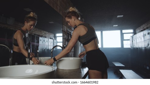 Beautiful Tall Sporty Blonde Woman Washing Face, Looking In The Mirror In Dark Gym Locker Room Exhausted Slow Motion.