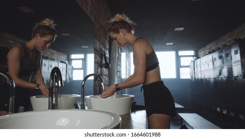 Beautiful Tall Sporty Blonde Woman Washing Face, Looking In The Mirror In Dark Gym Locker Room Exhausted Slow Motion.