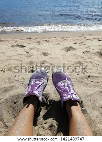 beautiful tanned female legs dressed in sneakers on the background of the sea