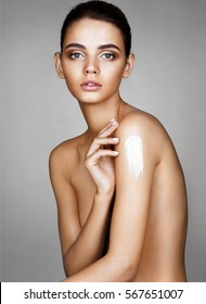 Beautiful tanned girl apply the moisturizer cream on body. Woman's shape with clean skin. Beauty & Skin care concept