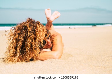 Beautiful Tanned Lady Middle Age Attractive With Curly Blonde Hair Lay Down At The Beach For A Summer Sun Bath During Vacation. Relaxed Attractive Woman In Summer Time In Holiday Vacation On The Sand