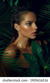 A beautiful tanned young woman with natural makeup and wet hair stands in the jungle among exotic plants. Tropical plants, nature