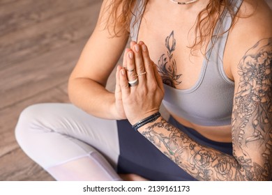 Beautiful tattooed young woman practicing yoga at home, closeup