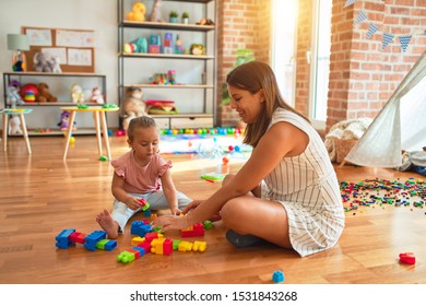 Beautiful teacher and blond toddler girl building tower using plastic blocks at kindergarten - Shutterstock ID 1531843268