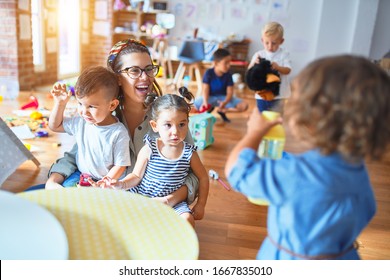 Beautiful teacher and group of toddlers playing around lots of toys at kindergarten - Shutterstock ID 1667835010