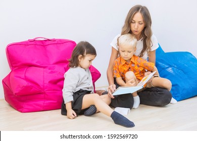 Beautiful Teacher Telling A Story With Her Two Pupils Calmly Observing In The Classroom