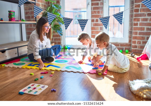 Beautiful teacher and toddlers playing with\
cars around lots of toys at\
kindergarten