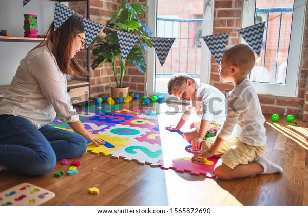 Beautiful teacher and toddlers playing with\
cars around lots of toys at\
kindergarten