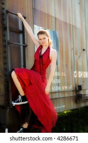 Beautiful Teen In Formalwear And Sneakers Climbing On A Rusty Old Boxcar.