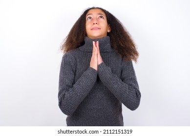 Beautiful Teen Girl With Afro Hairstyle Wearing Grey Turtleneck Sweater Against White Begging And Praying With Hands Together With Hope Expression On Face Very Emotional And Worried. Please God