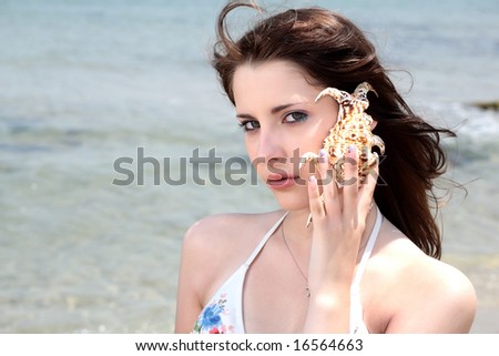beautiful teen girl in swimwear holding up a seashell